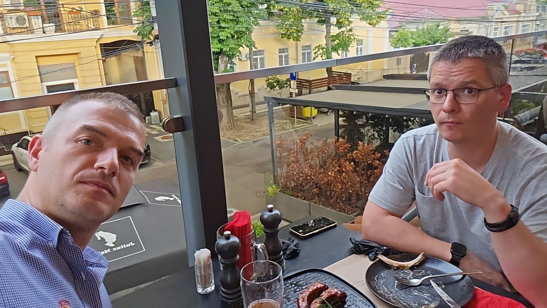 Two best friends sitting at an outdoor restaurant table with beer and food